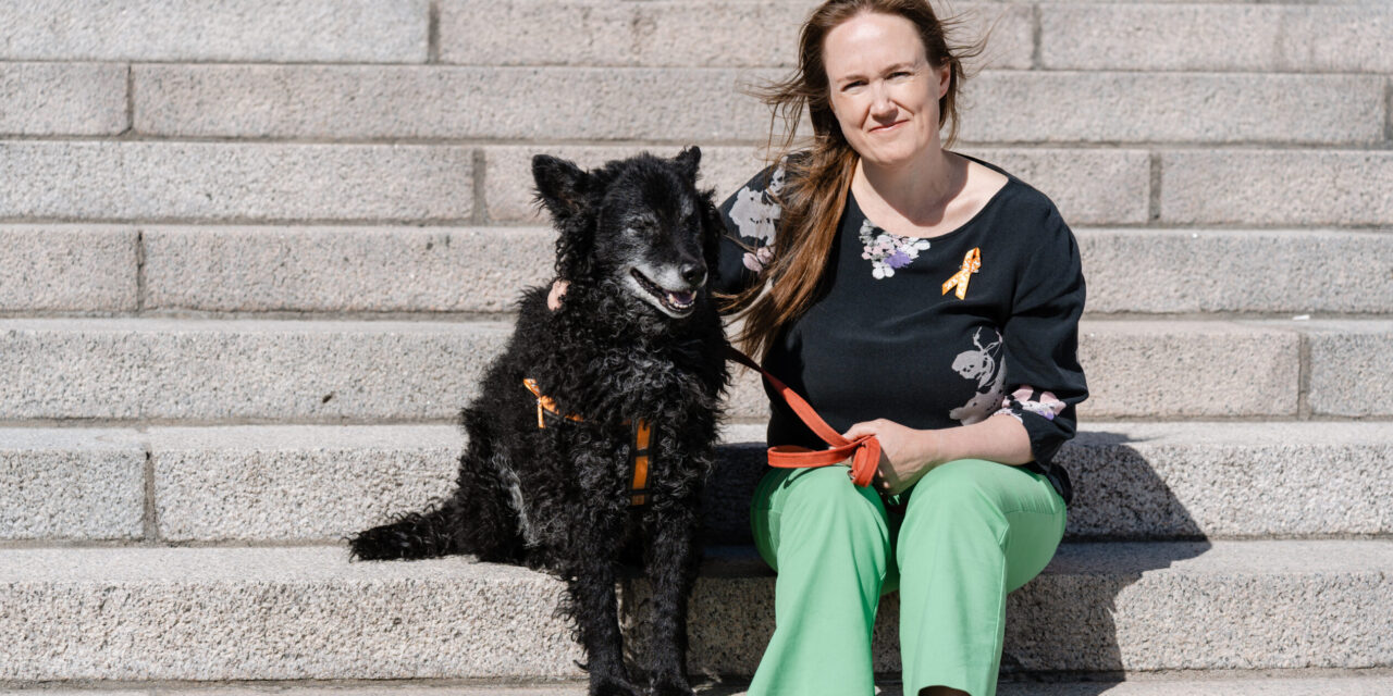 Kati White ja musta koira istumassa portailla.